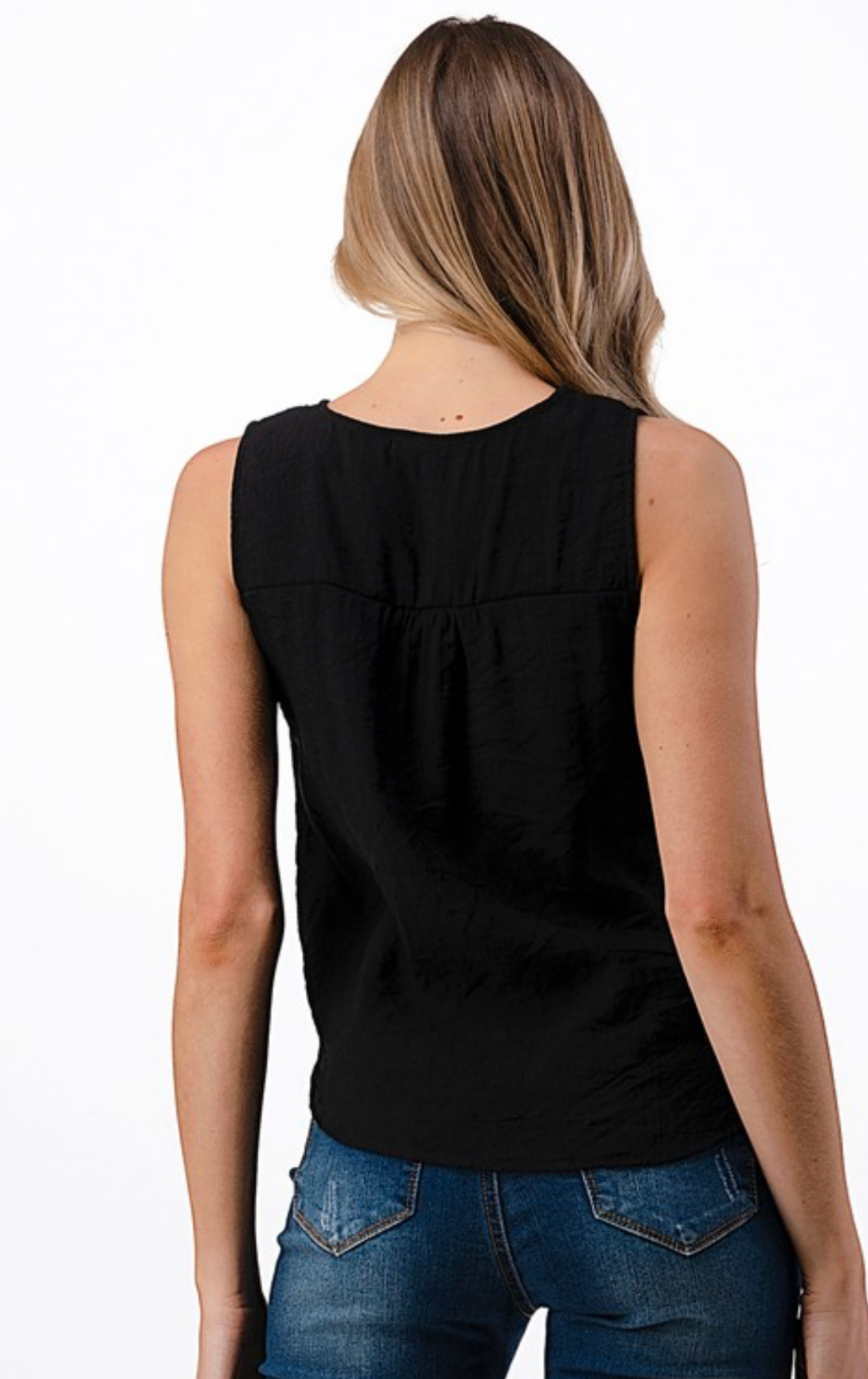 Woman wearing a black sleeveless top and blue jeans on a white background