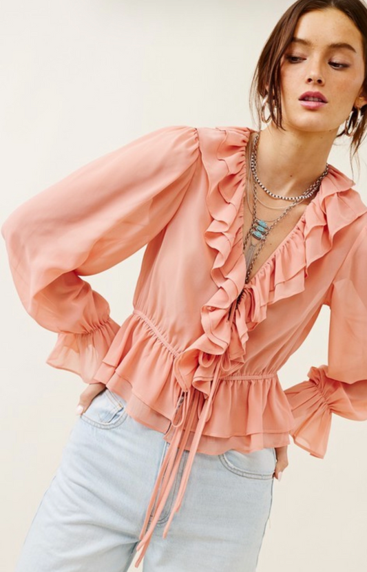 Woman wearing a pink ruffled blouse with a plain background