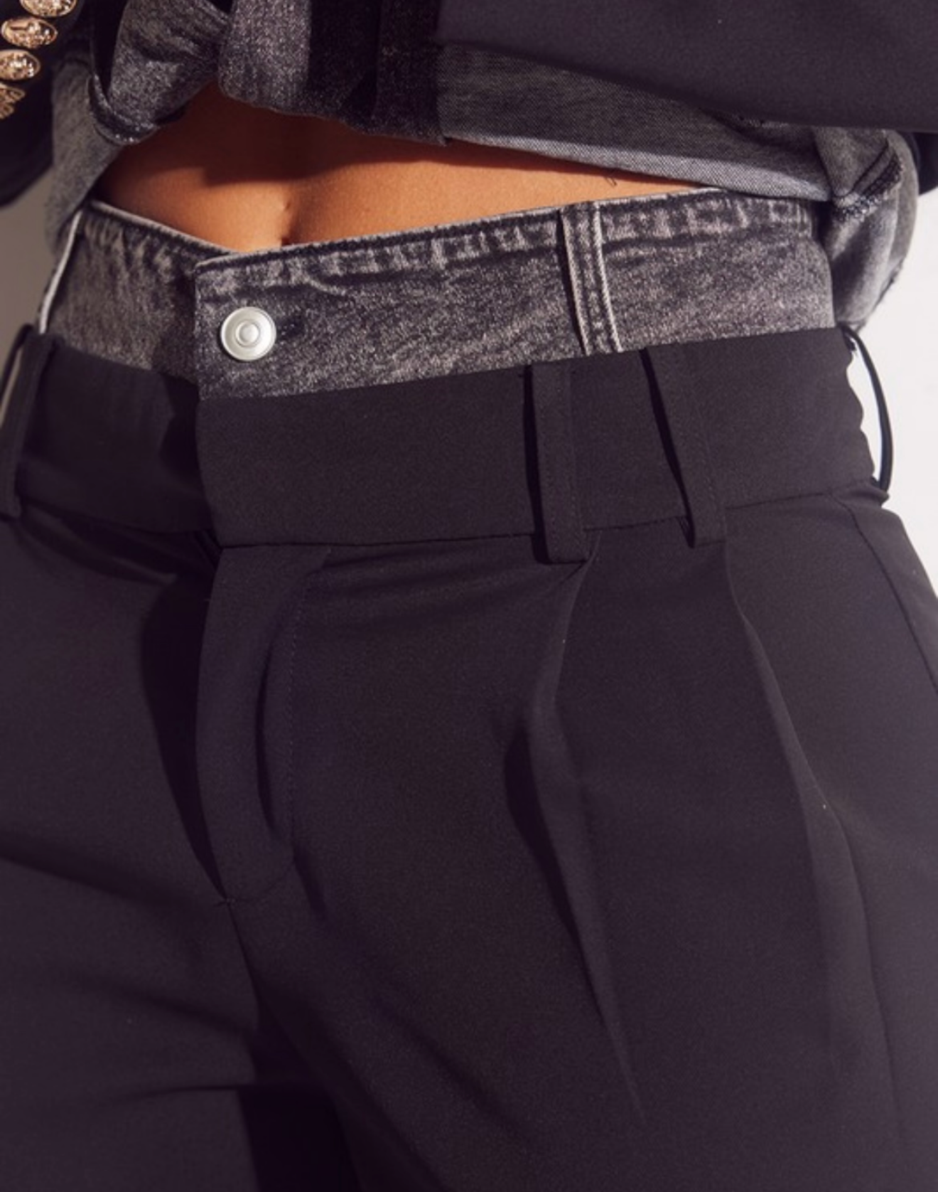 Close-up of black pants with a gray waistband and button.