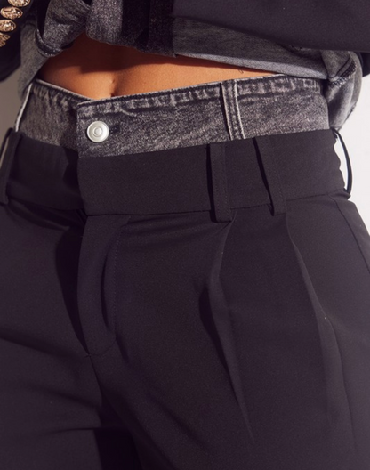 Close-up of black pants with a gray waistband and button.