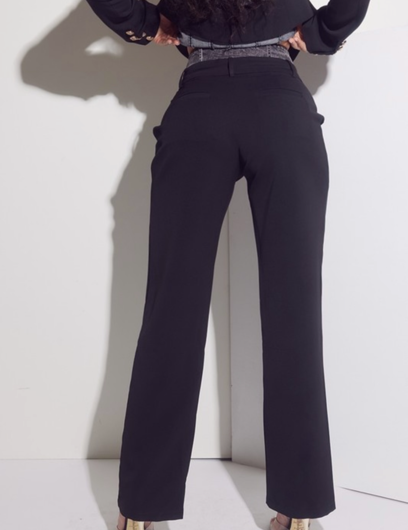 Person wearing black high-waisted pants against a white background